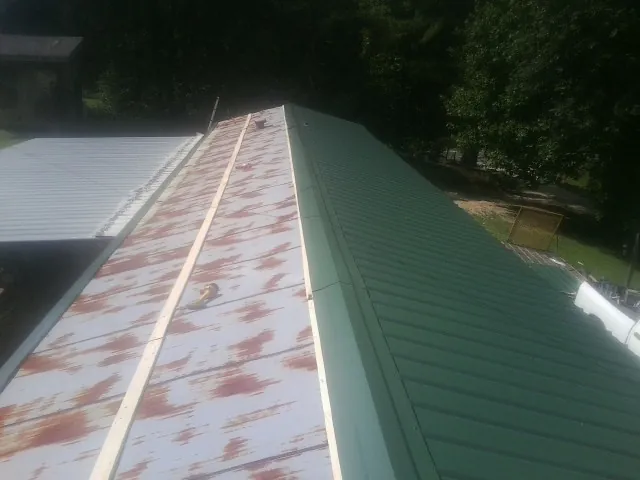 Old rusted panels beside newly installed green metal roofing — Wind Damage Roof Repair by Roofing Brothers in Sperry