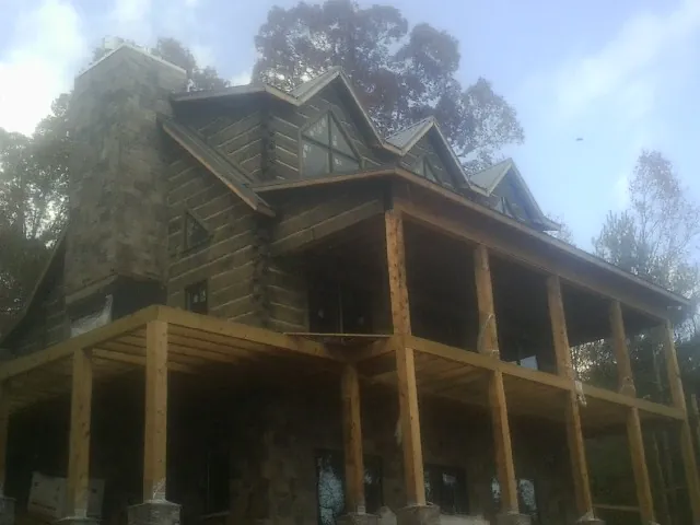 Stone chimney and dormers on a large log home with a timber porch in Sperry