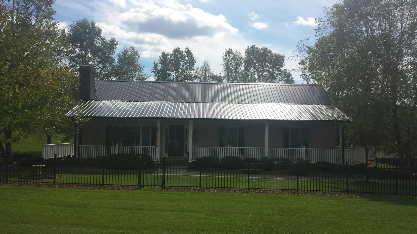 Gray metal roof on a brick ranch with a full width front porch — Gutter Guard Installation work by our crew in Sperry