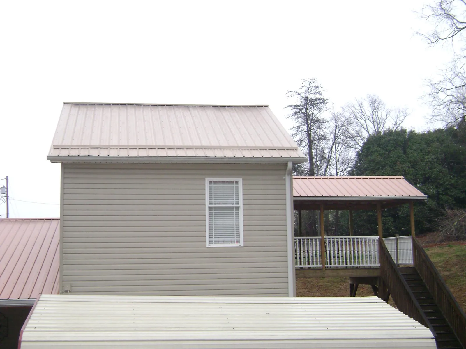 Tan metal roofs on a two story addition and attached porch, from a Roof Replacement job in Sperry